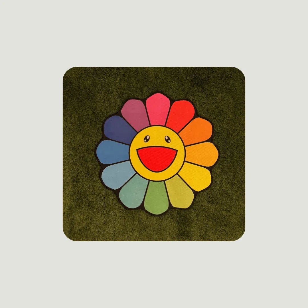 Rainbow Flower Rugs in multiple sizes laid out on green turf to showcase sizing and bright color contrast.