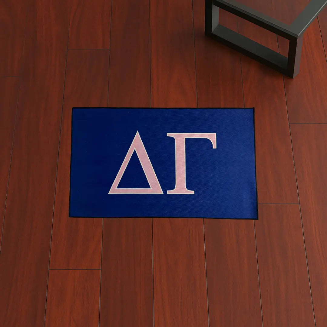 Custom Rug – Delta Gamma Letters Pink & Blue custom rug by Sirenicate Rugs, prominently displayed on a vibrant dark hardwood floor background.