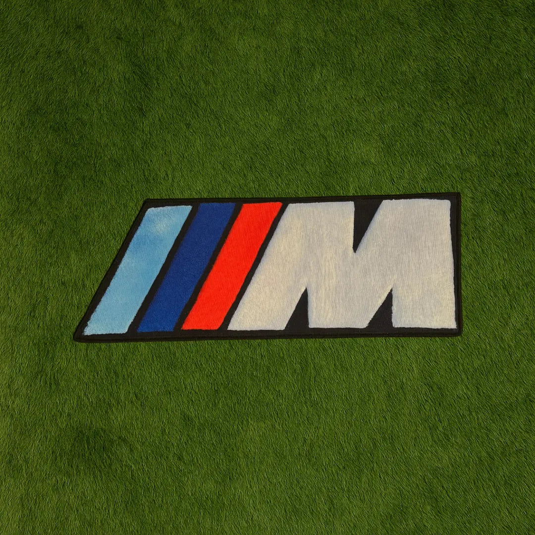 Sport M Logo Design Custom Rug by Sirenicate Rugs, prominently displayed on a vibrant dark green turf background.