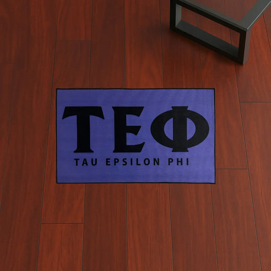 Custom Rug – Tau Epsilon Phi Letters Purple & Black custom rug by Sirenicate Rugs, prominently displayed on a vibrant dark hardwood floor background.