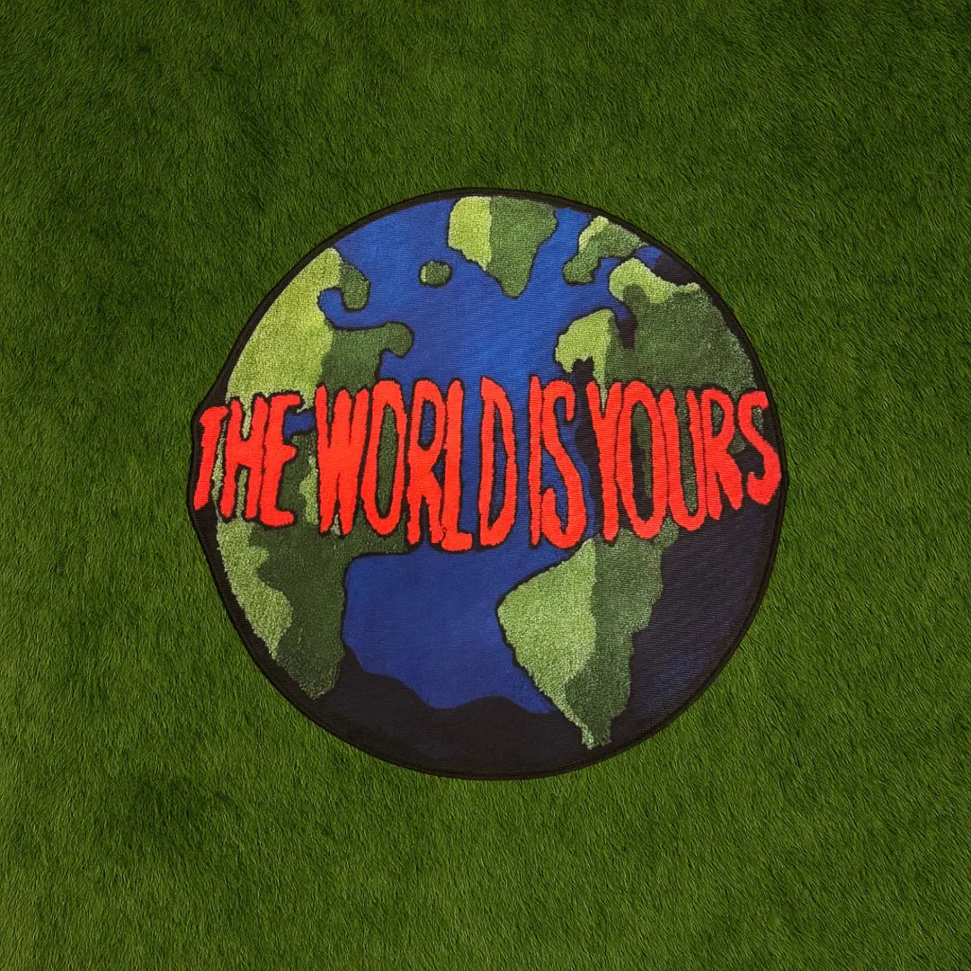 The World Is Yours Custom Rug by Sirenicate Rugs, prominently displayed on a vibrant dark green turf background.