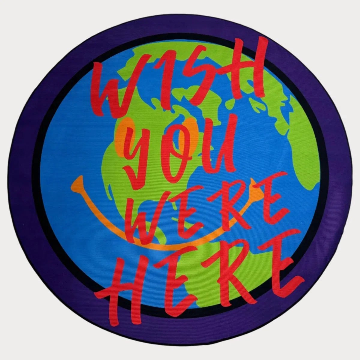 Custom “Wish You Were Here” circular rug featuring red text and globe design, laid flat on a white background.
