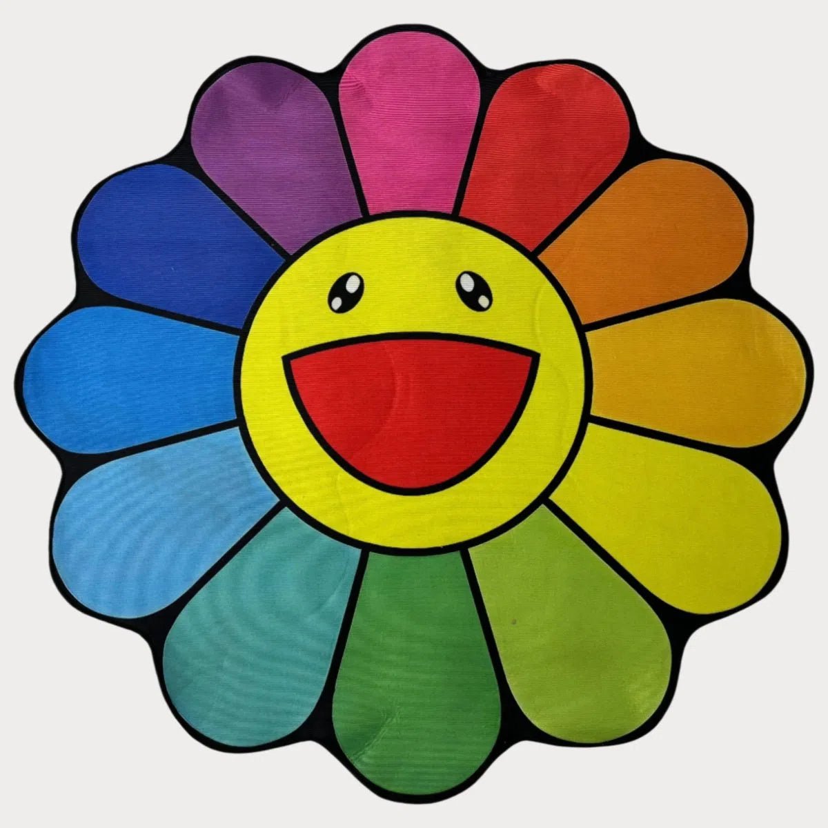 Rainbow Marukami Flower Rug featuring a smiling face with vibrant multicolored petals, laid flat on a clean surface.